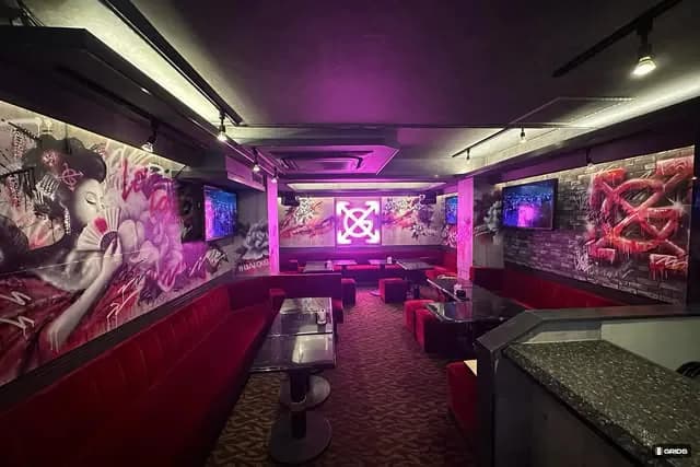 祇園店の店内。赤いソファと壁画、ネオンのXGマーク